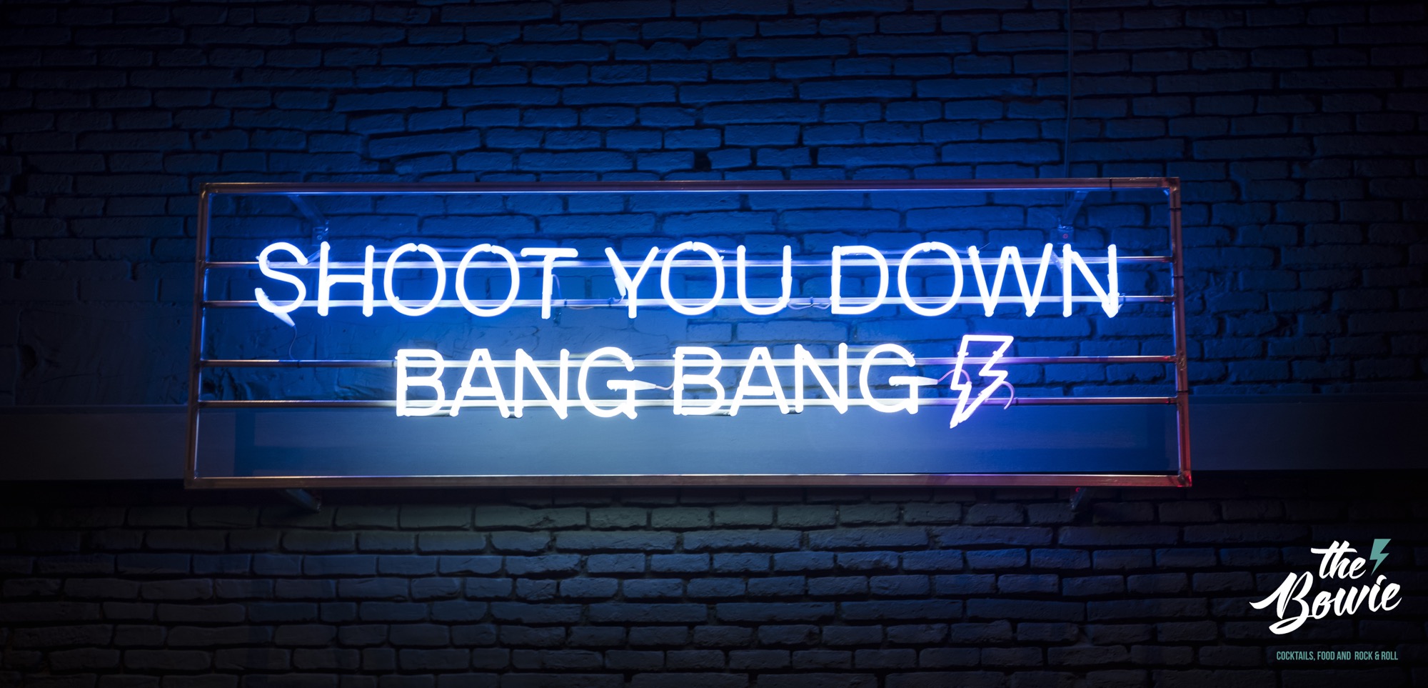 Rótulo de neón del local: «Shoot you down, bang bang», con el rayo de The Bowie